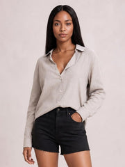 Model wearing a light beige textured button-front shirt with a collared neckline, long sleeves, relaxed regular silhouette, and curved hem.