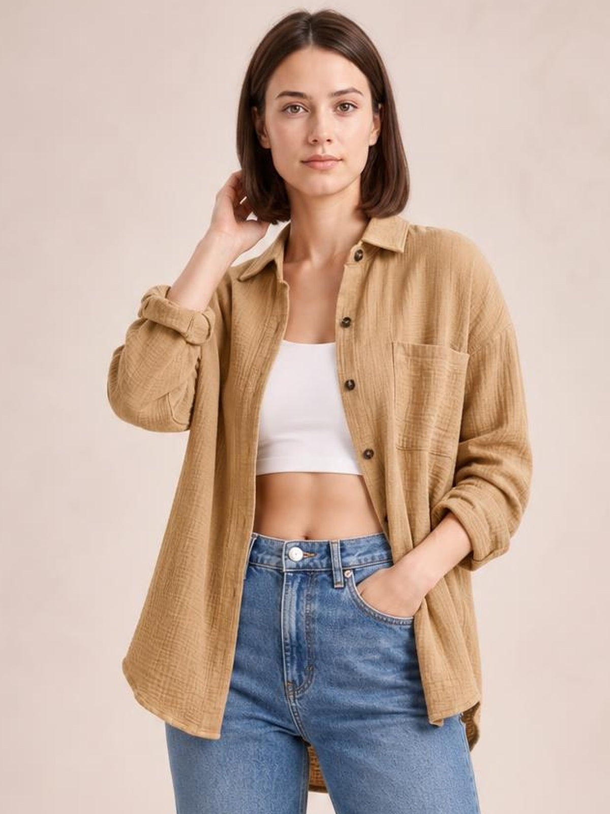 Model poses in a textured tan longline shirt with dropped shoulders, collared neckline, button front, chest pocket, and rolled long sleeves.