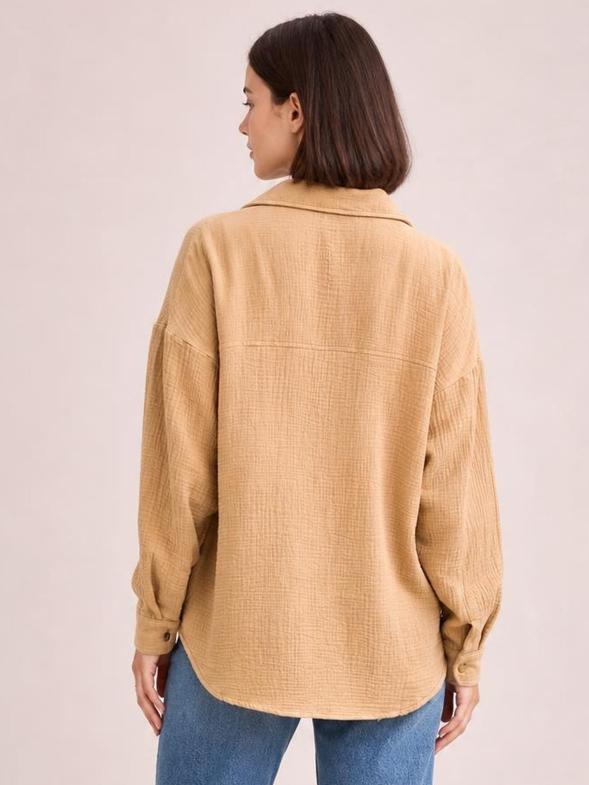 Model shown from the back wearing a textured tan longline shirt with a collared neckline, dropped shoulders, long sleeves, cuffs, and a relaxed silhouette.
