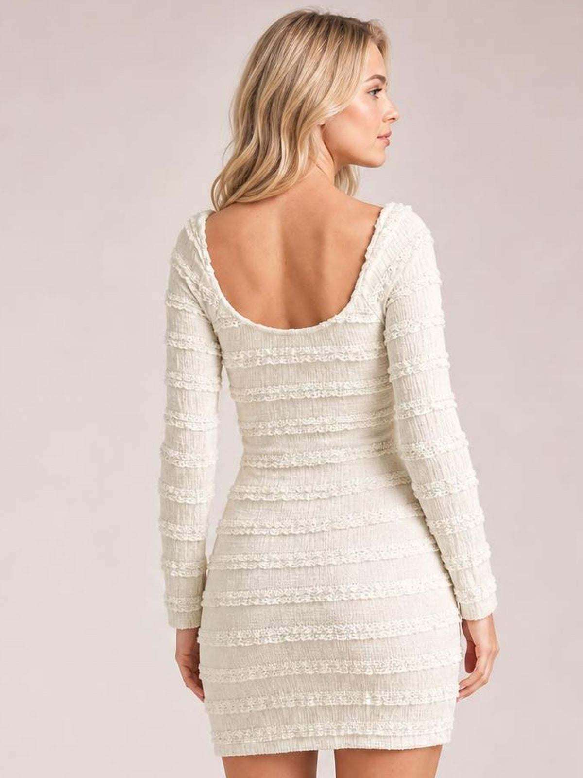 Model shown from behind in a white textured long-sleeve bodycon mini dress with a low scoop back, fitted silhouette, and raised horizontal bands.