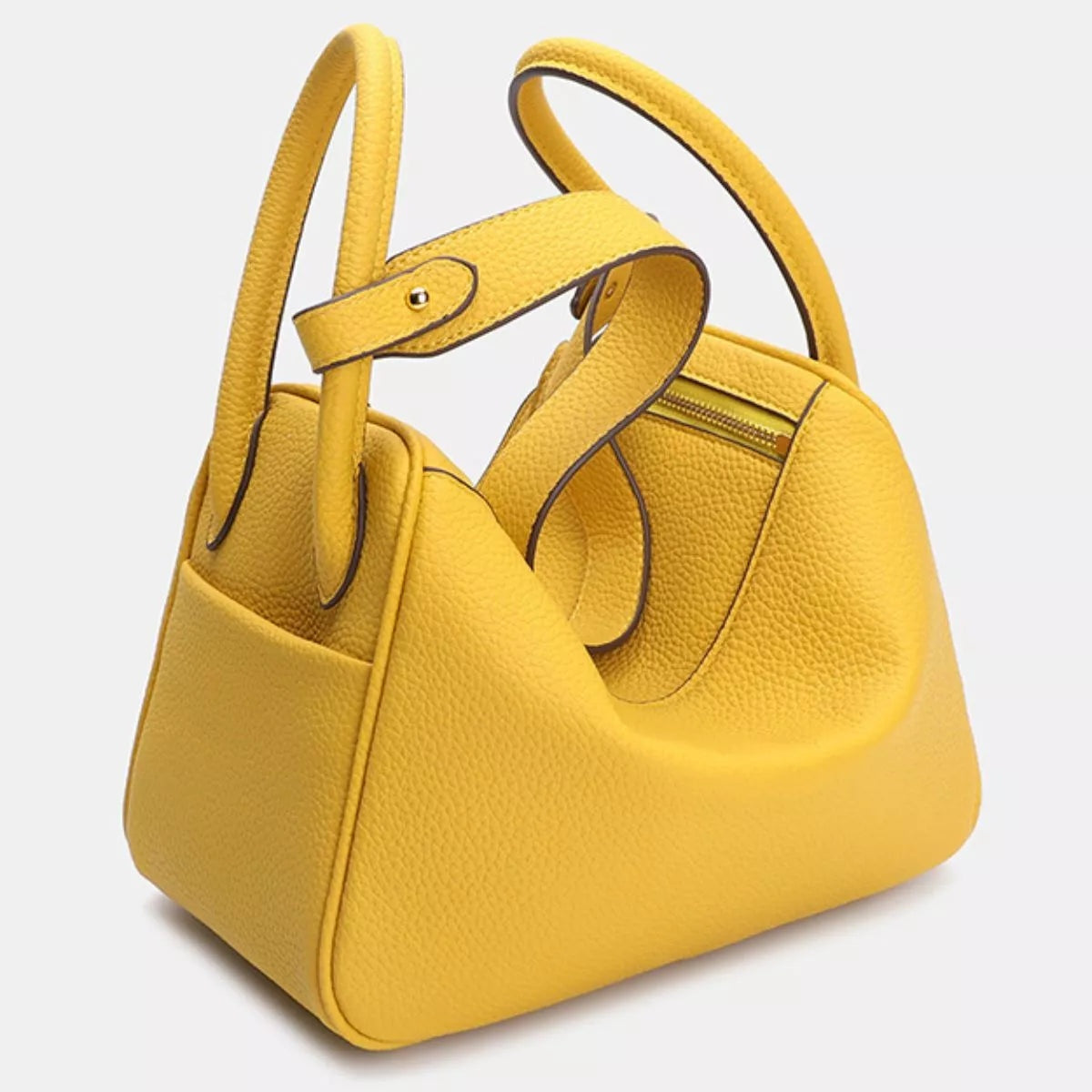 Small yellow textured PU leather handbag with a structured trapezoid silhouette, double top handles, dark edge piping, and a visible zippered pocket.