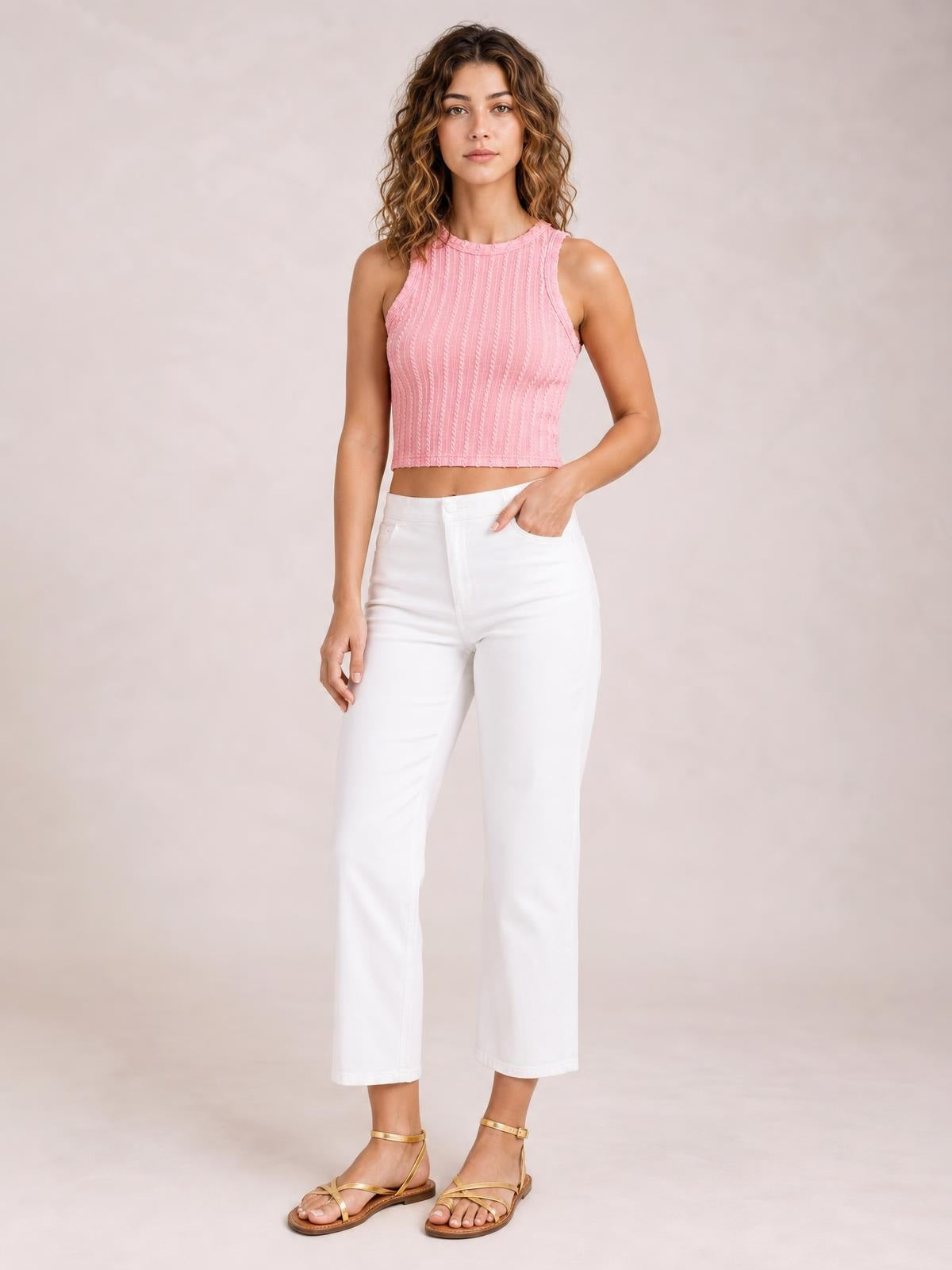 Model poses in a pink textured racerback cropped tank with a fitted silhouette, ribbed vertical construction, and wide shoulder straps.