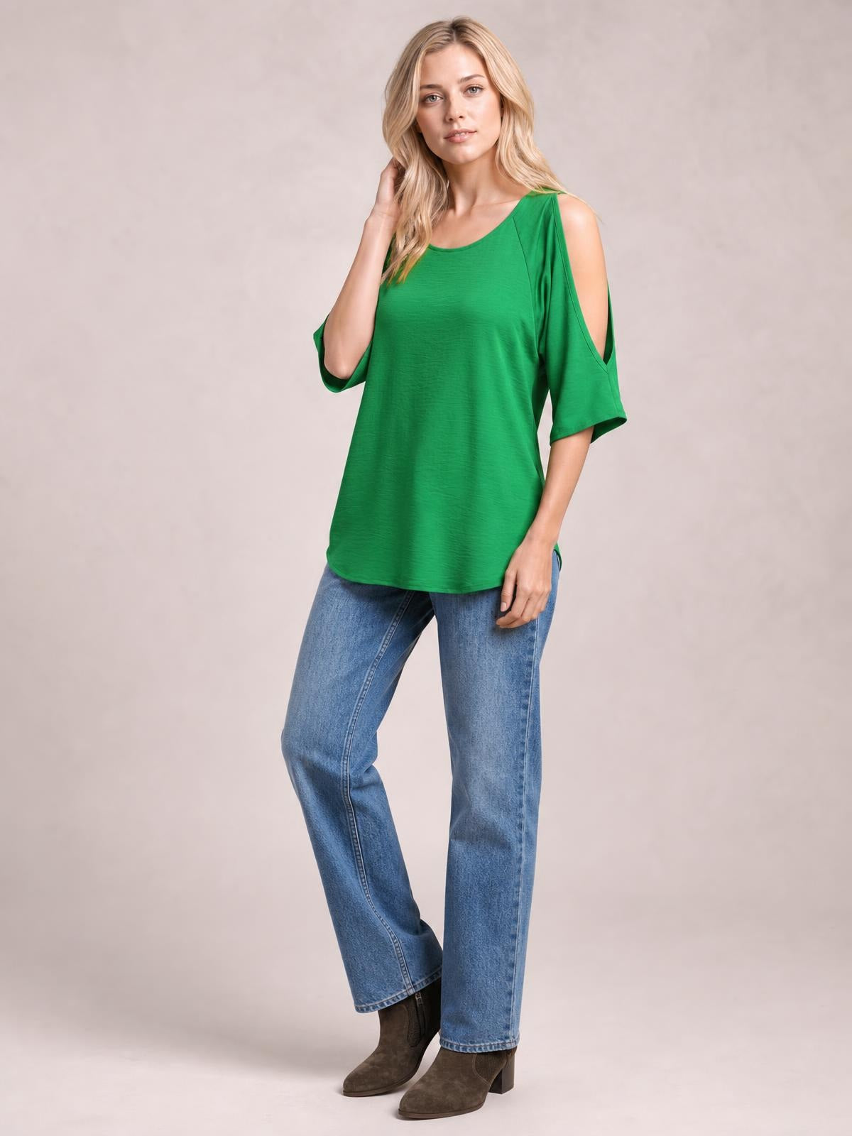 Model poses in a green textured round-neck top with long, relaxed silhouette and cold-shoulder split sleeves, one hand touching her hair.