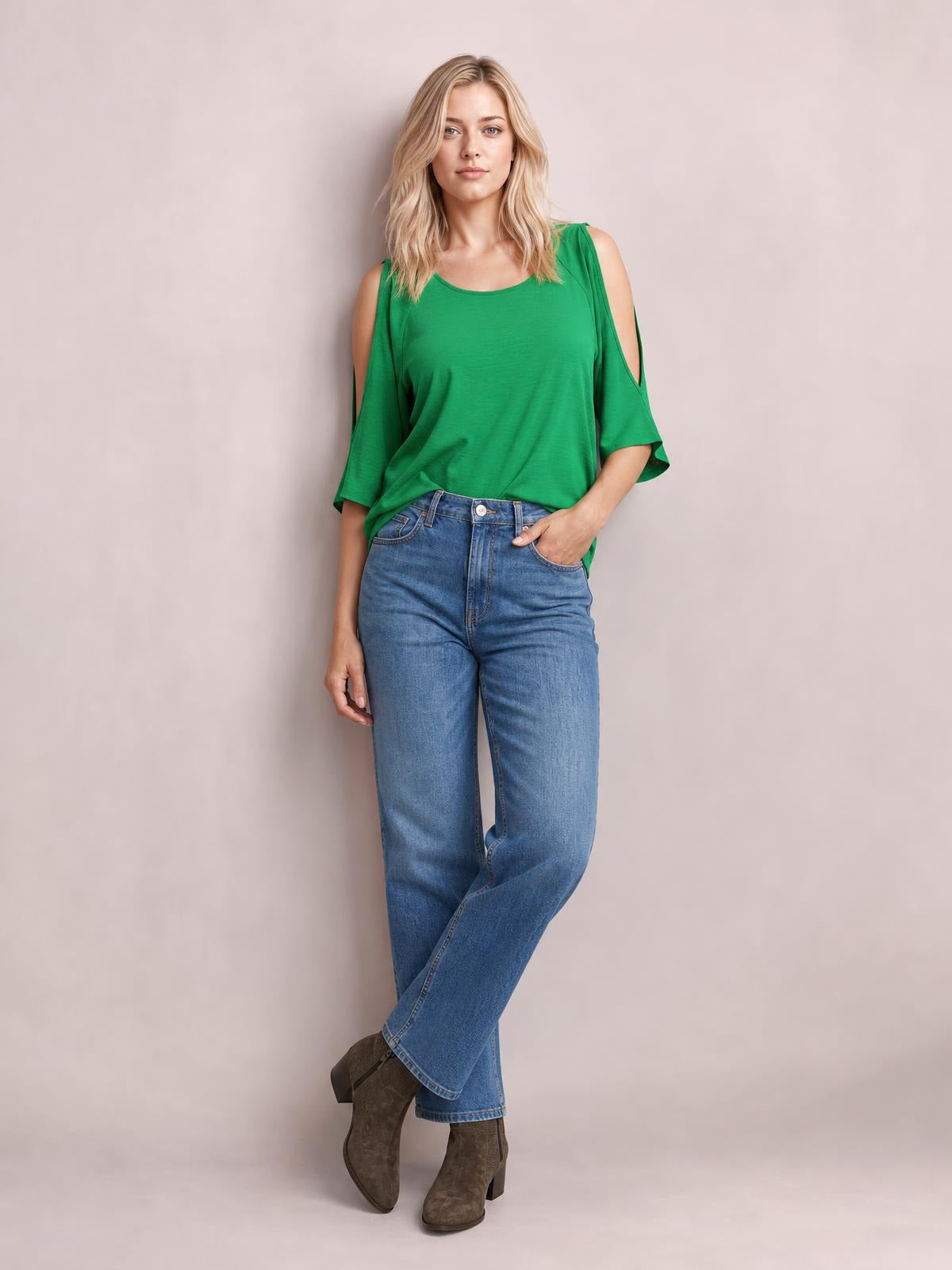 Model poses in a solid green textured round-neck top with a long relaxed silhouette, cold-shoulder split sleeves, and a hand resting in her jeans pocket.