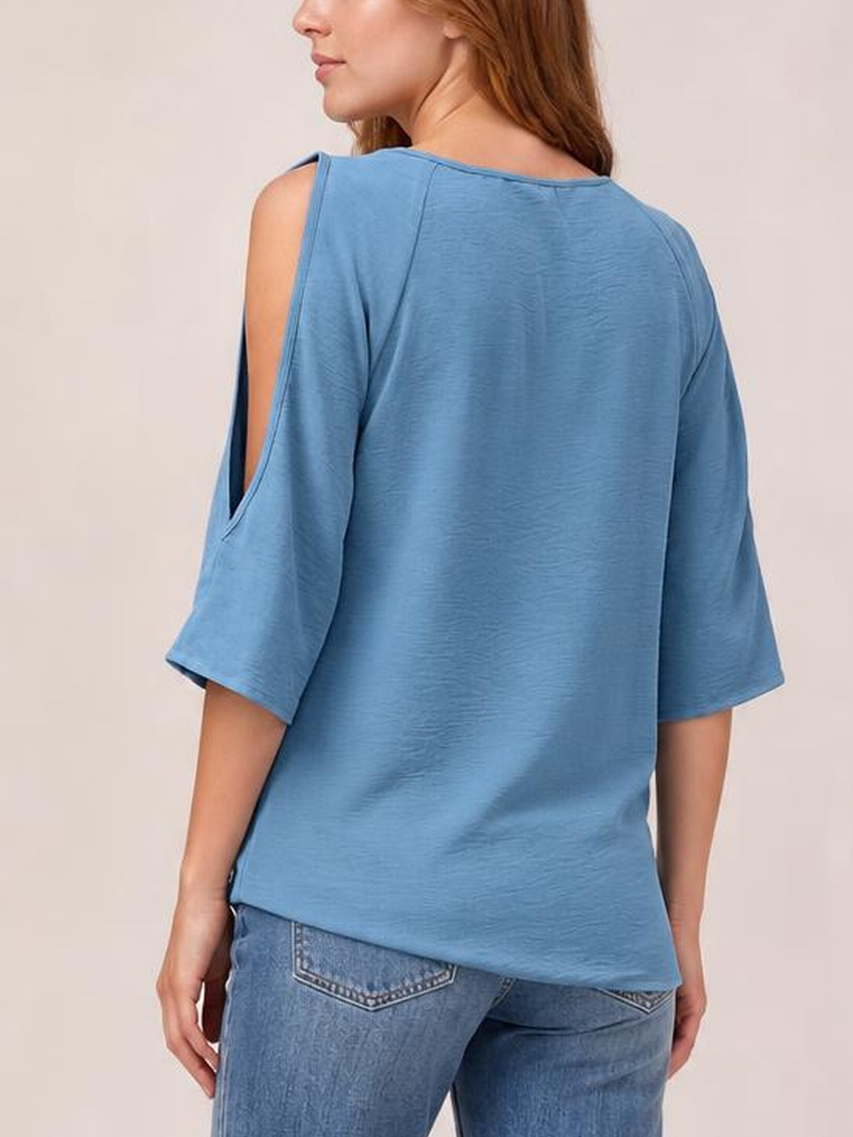 Model turned away in a blue textured round-neck top with a relaxed long silhouette, half sleeves, and open cold-shoulder split sleeve details.