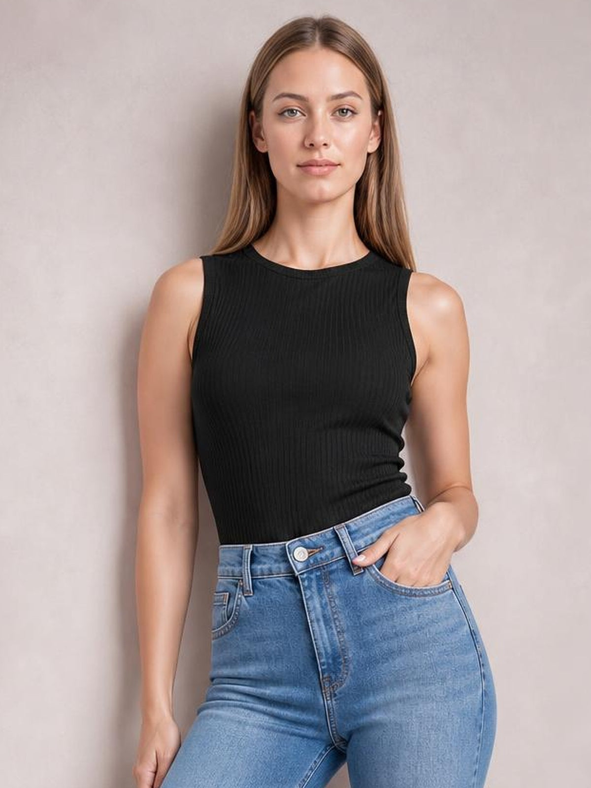 Model wearing a black textured round neck tank with a fitted sleeveless silhouette, paired with blue jeans and one hand resting in a pocket.