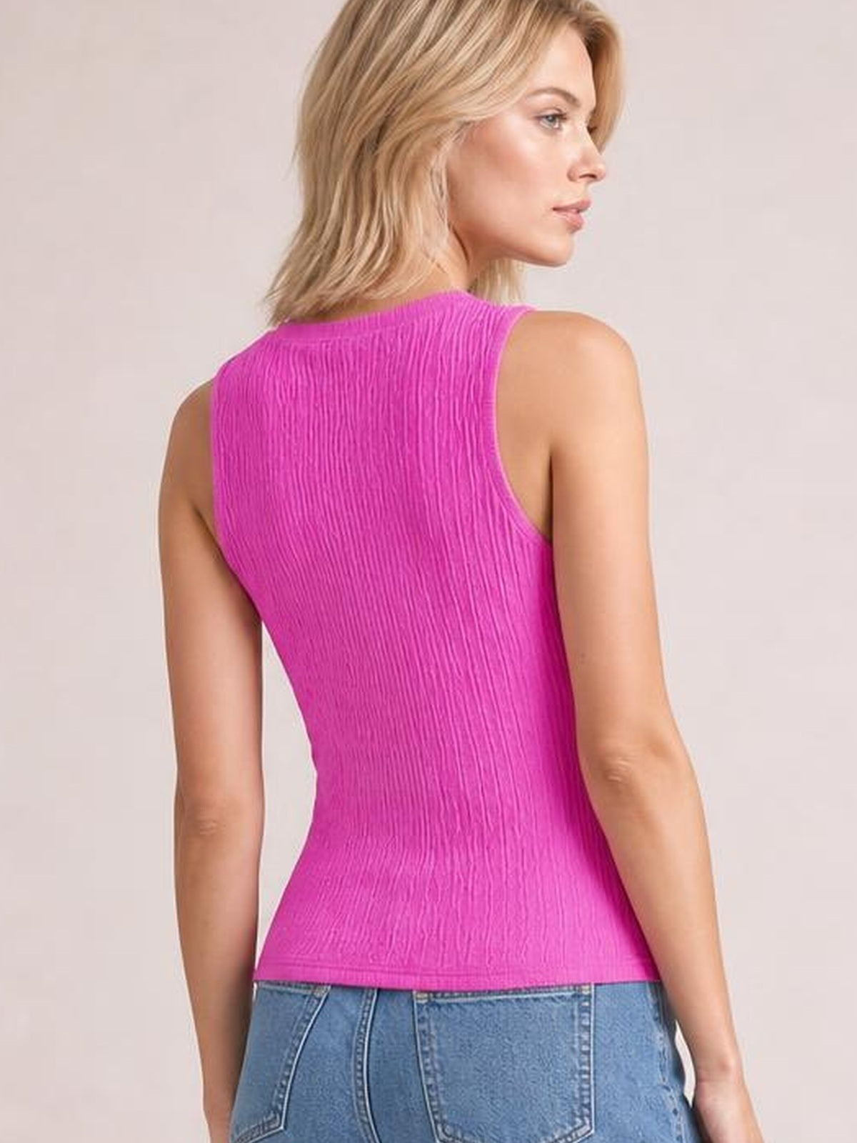 Model turned to the side shows a bright pink textured tank with a round neck, wide shoulder straps, fitted silhouette, and straight hem.