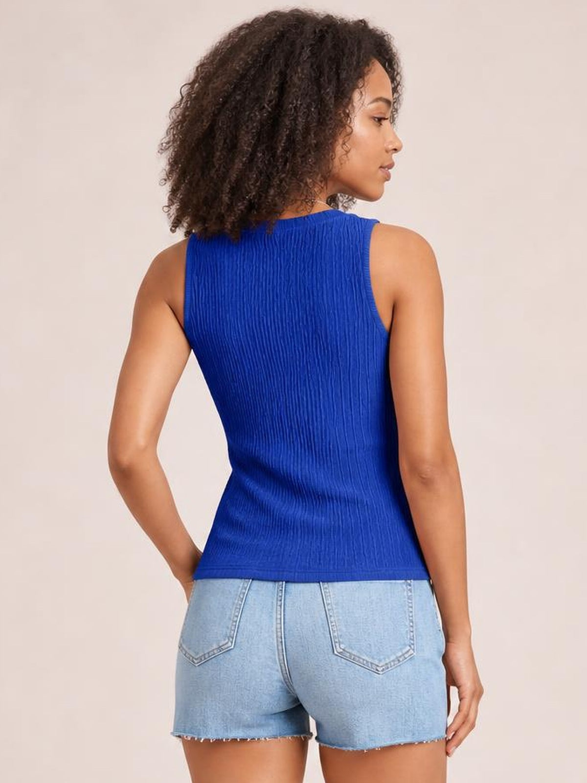 Model poses in a bright blue textured round neck tank with a fitted sleeveless silhouette and straight hem, shown from the back.