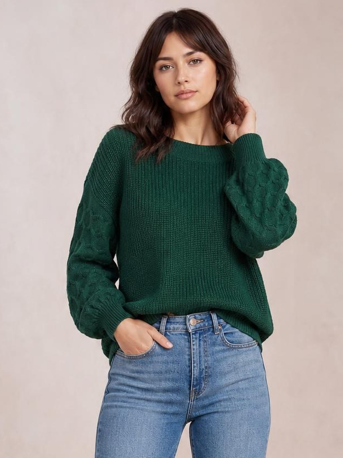 A model poses in a dark green textured sleeve round neck sweater with a relaxed silhouette, ribbed cuffs, and raised patterned sleeves.