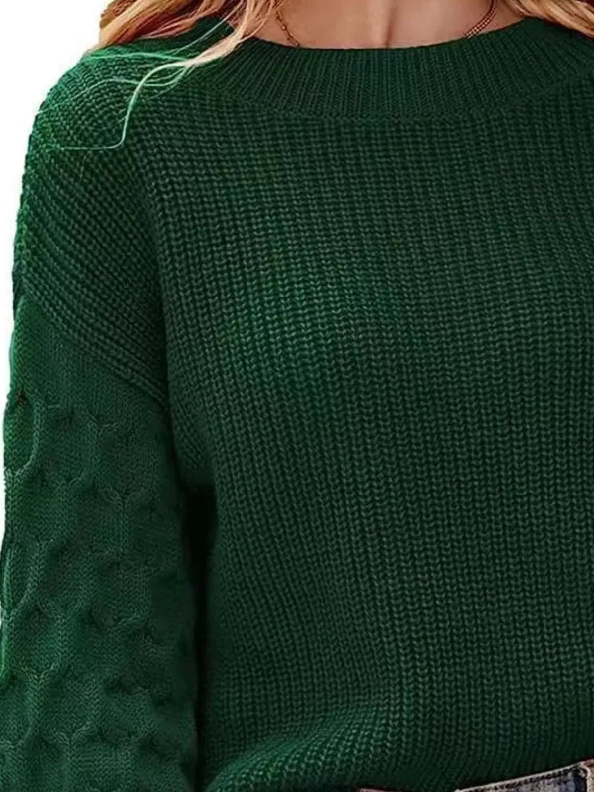 Close-up of a model wearing a dark green textured sweater with a round ribbed neckline, stretchy knit construction, and contrasting patterned sleeves.
