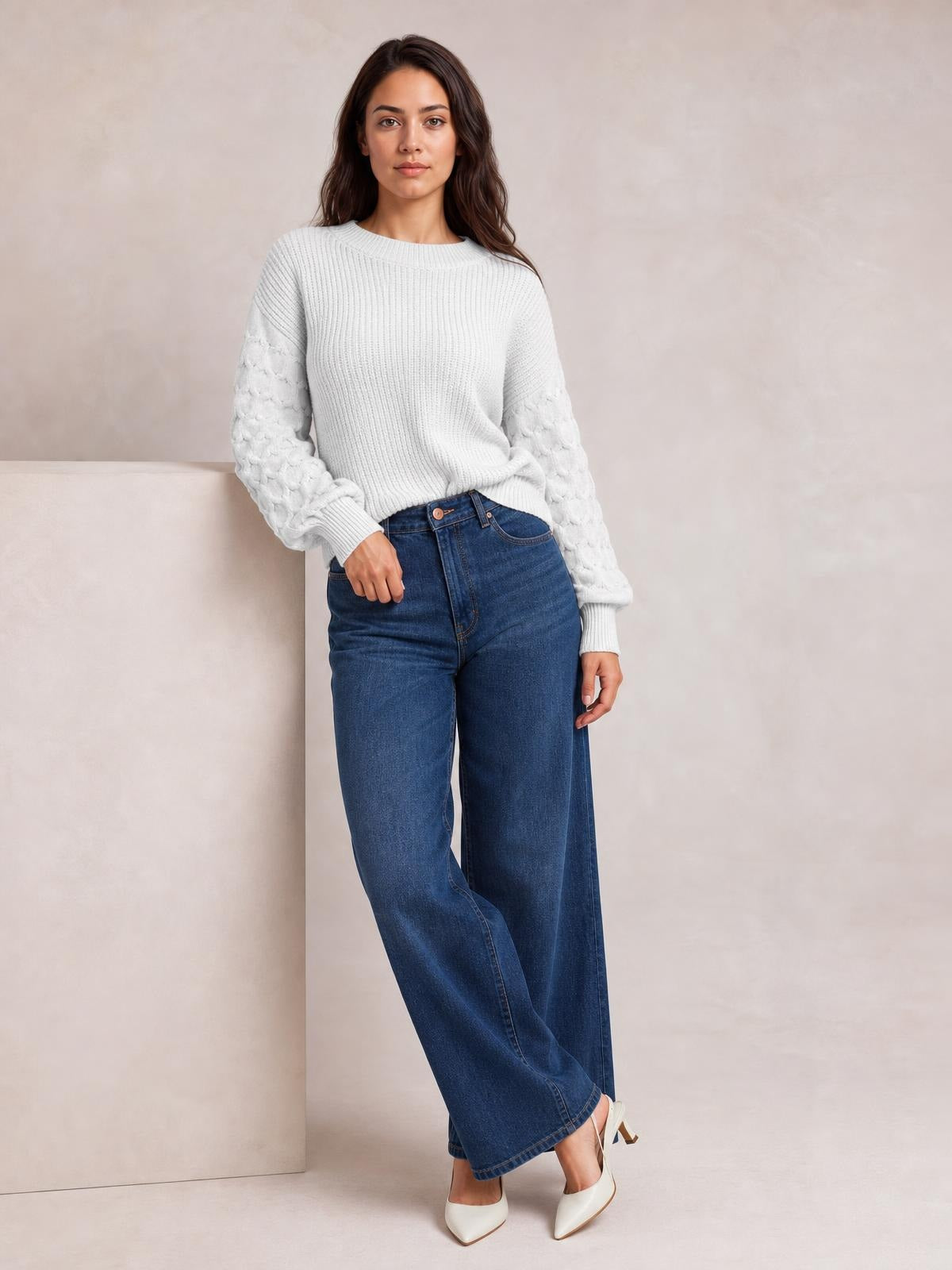 A model poses in a white round-neck sweater with a ribbed body, textured sleeves, dropped shoulders, ribbed cuffs, and a relaxed silhouette.
