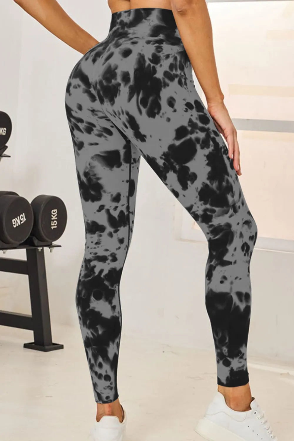 A model poses in gray and black tie-dye high-waist active leggings with a fitted full-length silhouette and slight stretch.