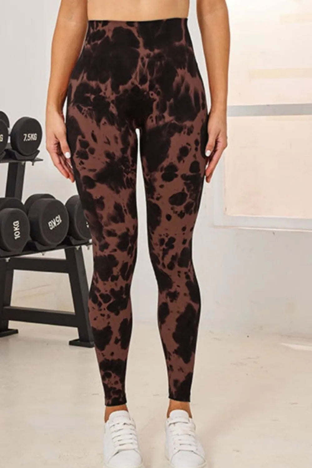 Model stands with hands at her sides wearing brown and black tie-dye high-waist active leggings in a fitted full-length silhouette.