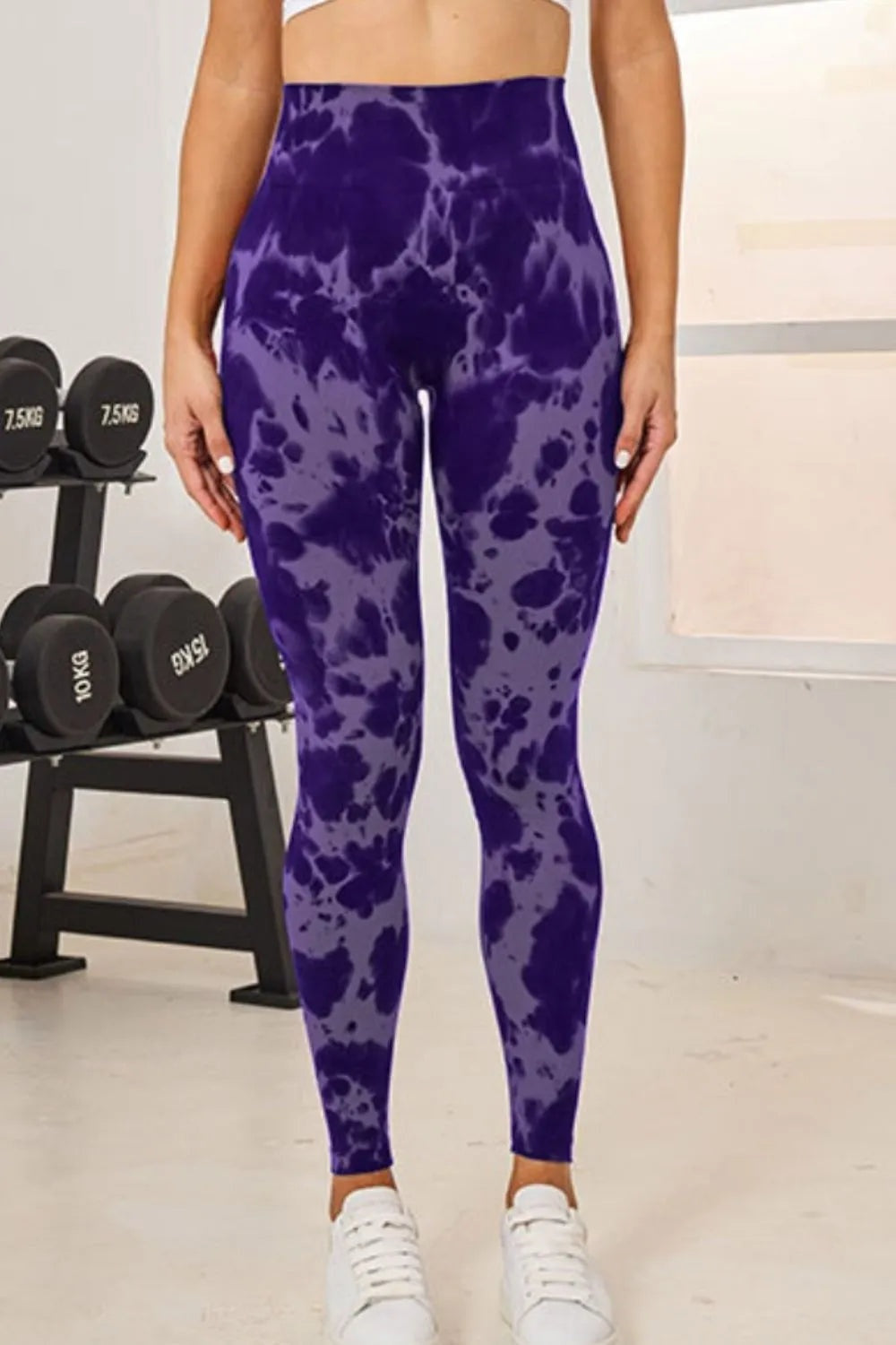Model stands with hands at her sides wearing purple tie-dye high-waist active leggings in a fitted, full-length silhouette.