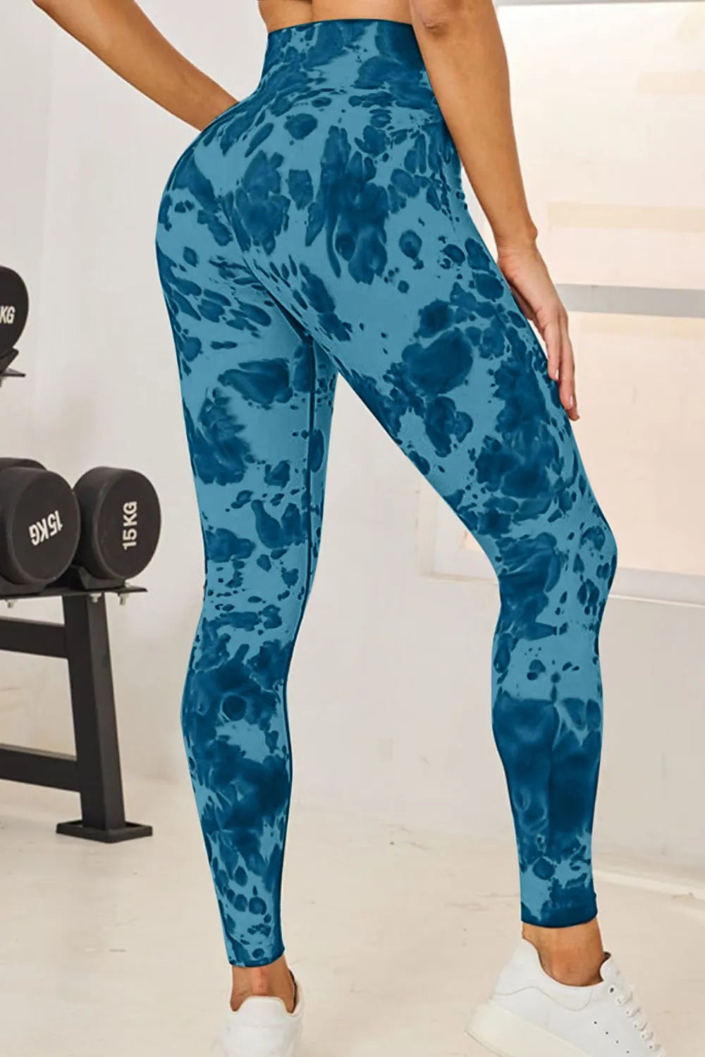 Model poses in blue tie-dye high-waist active leggings with a fitted full-length silhouette and stretchy construction.