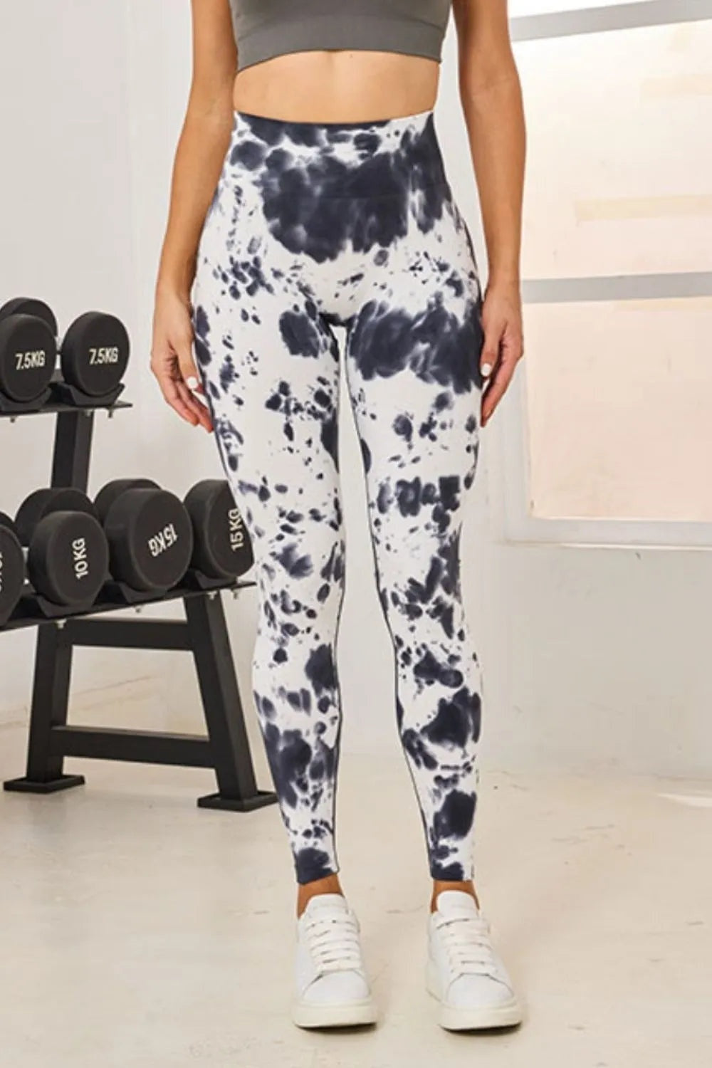 Model stands facing forward in tie-dye high-waist active leggings with a white and navy blotched pattern, fitted full-length silhouette, and slight stretch.