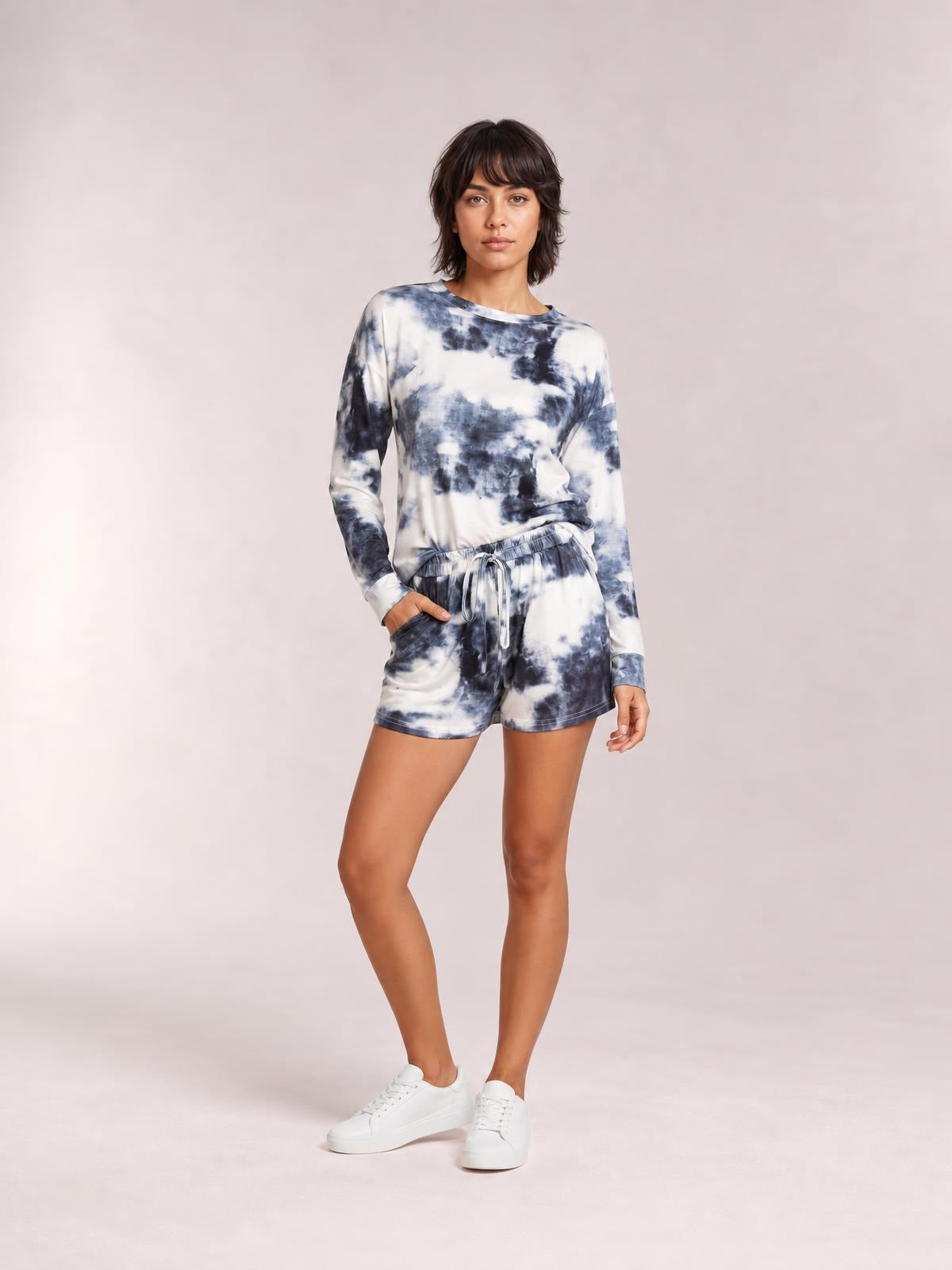 A model poses in a navy-and-white tie-dye lounge set with a round-neck long-sleeve top, relaxed silhouette, and drawstring shorts.