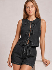 A model wears a dark denim tie-front sleeveless top with multiple bows and a relaxed cropped silhouette, paired with matching high-waisted shorts.