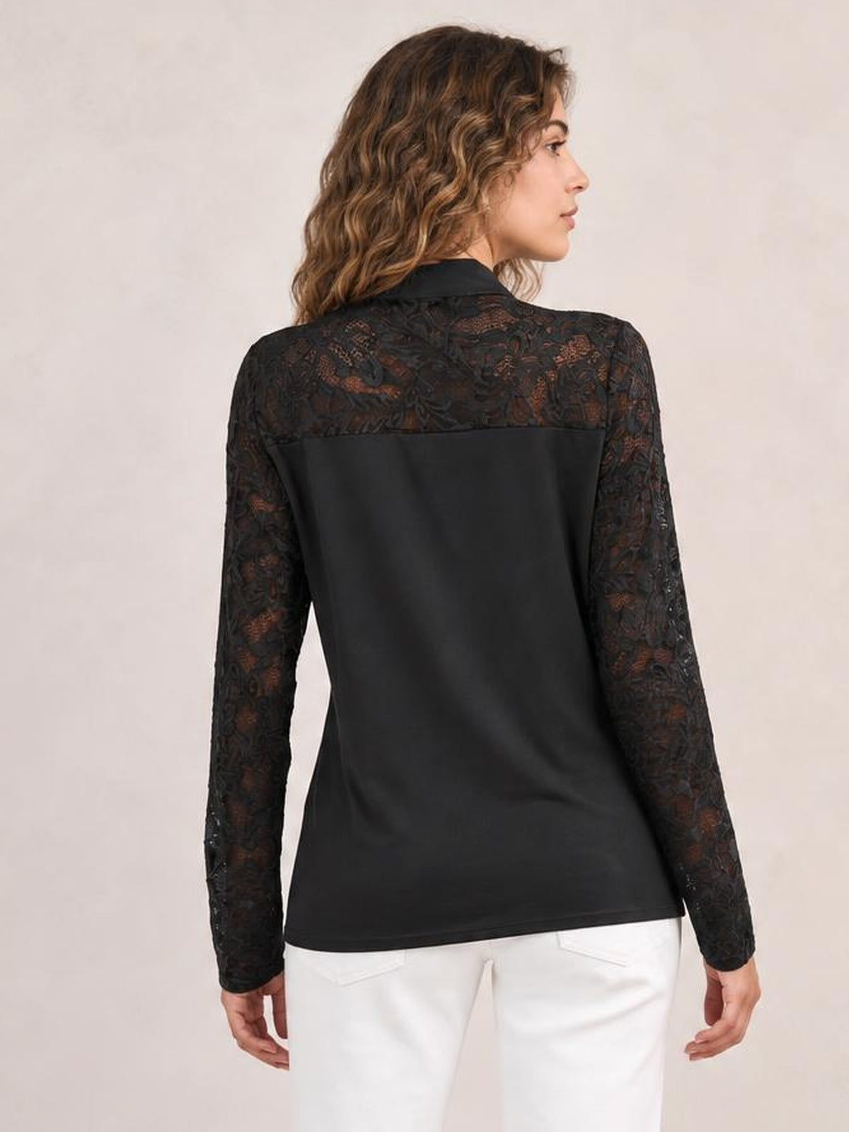 Model shown from behind in a black blouse with floral lace long sleeves and upper back, a smooth regular-length body, and a relaxed straight silhouette.