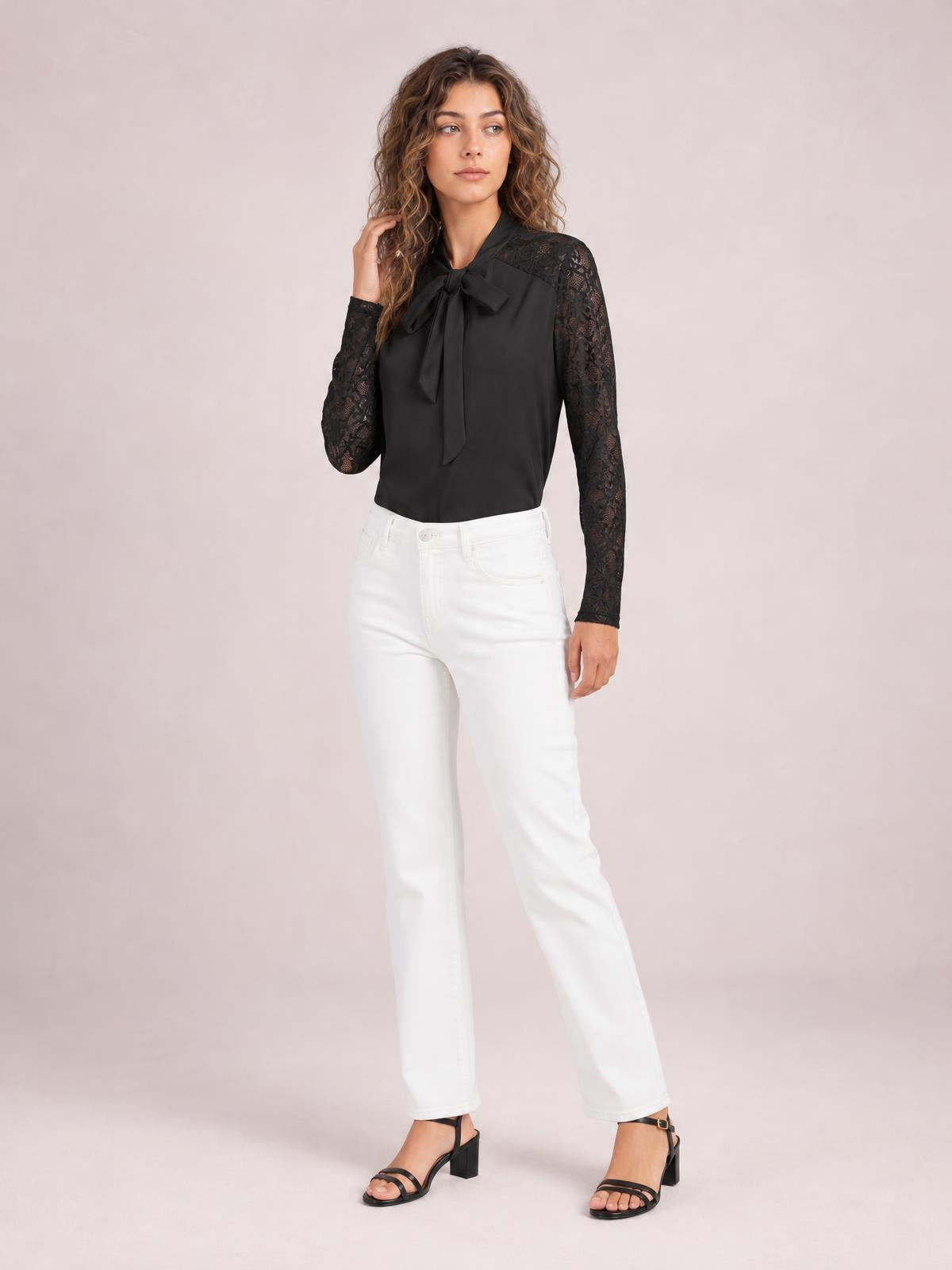 Model poses in a black tie-neck blouse with a bow front, lace long sleeves, solid fabric, and a regular straight silhouette.