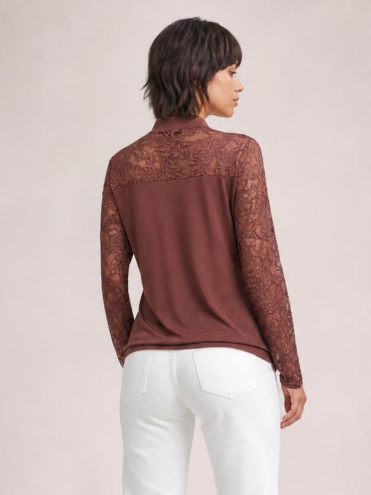 Model turned away in a brown tie-neck top with long lace sleeves and a spliced lace back yoke, showing its regular relaxed silhouette.