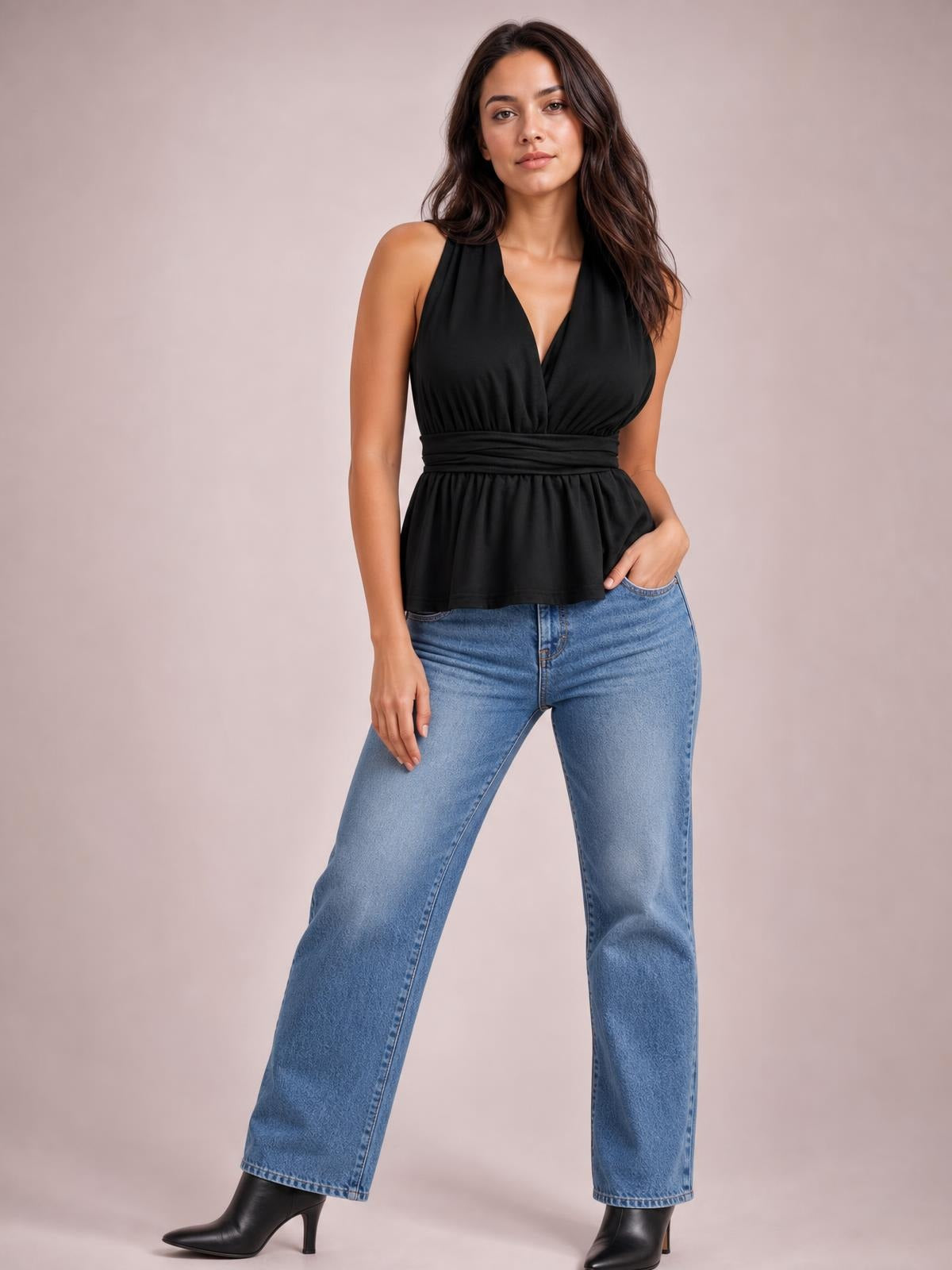 Model poses in a black sleeveless peplum top with a deep V-neckline, crisscross front, ruched waist, and flared hem.