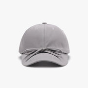 Gray cotton baseball cap with a softly rounded paneled crown, curved brim, neat topstitching, and a tied bow detail across the front.
