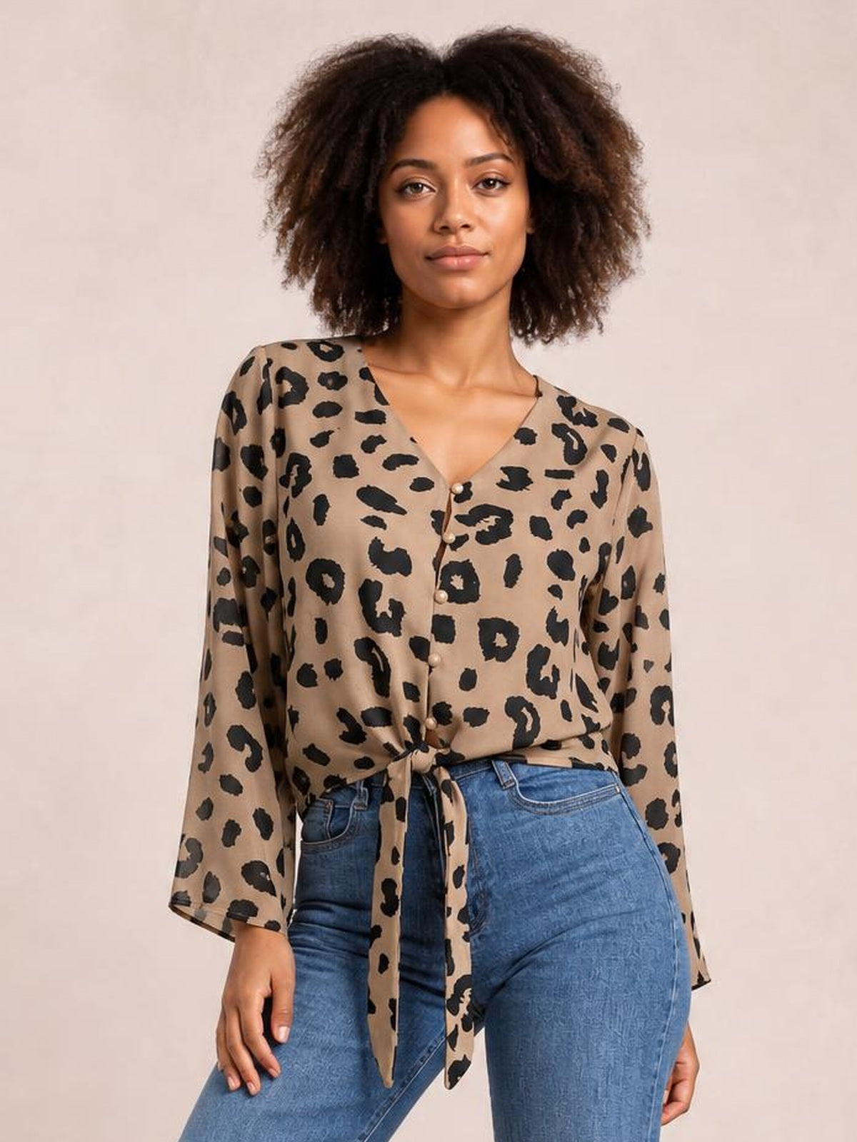 Model wearing a tan leopard print blouse with a V-neck, button front, long sleeves, and a tied waist creating a relaxed silhouette.