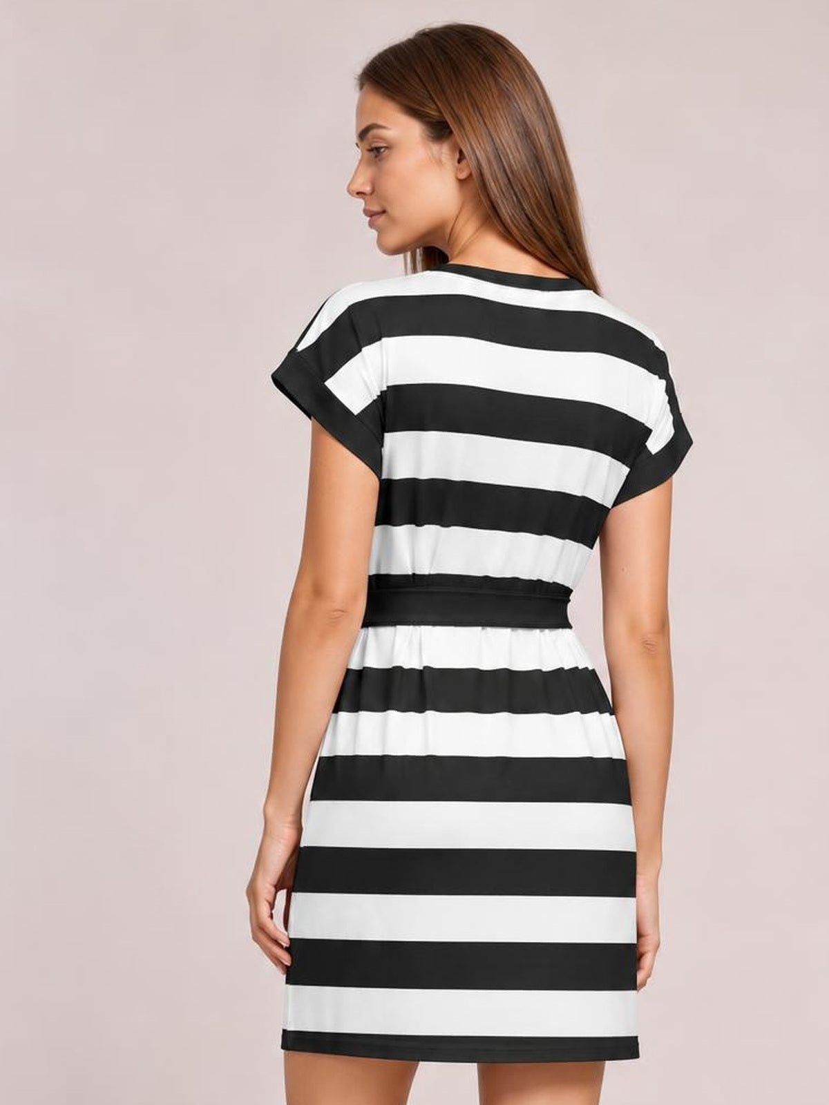 Model shown from behind wearing a black-and-white contrast striped mini tee dress with short sleeves, a tied waist, and a straight silhouette.