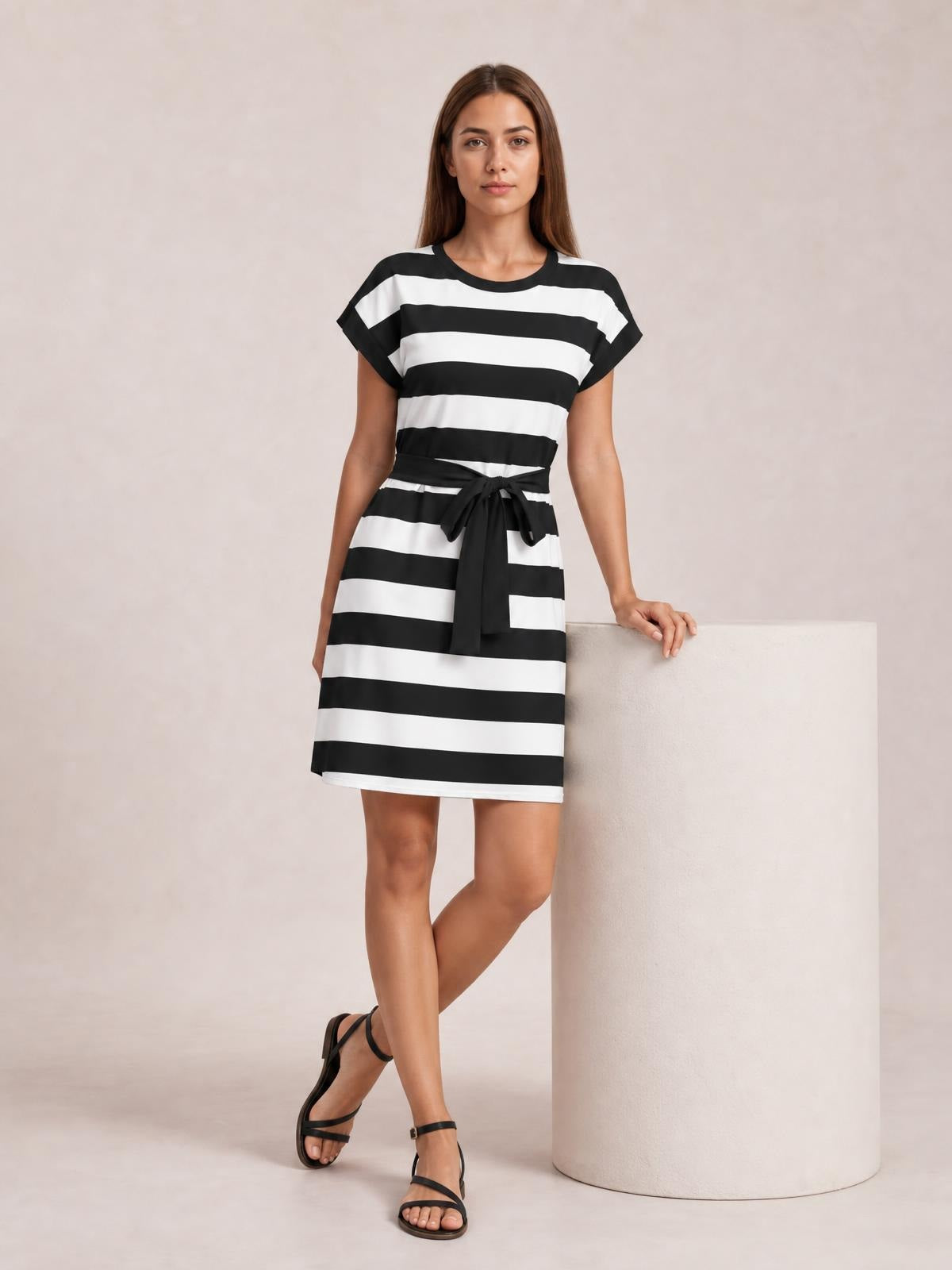 Model wears a black-and-white contrast striped mini tee dress with short sleeves, a straight silhouette, and a tied waist belt.