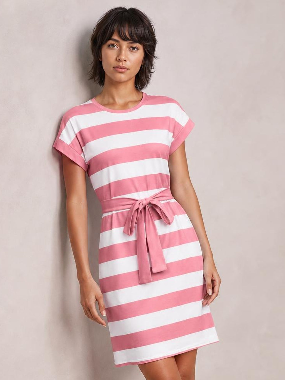 Model wears a pink and white striped short-sleeve mini tee dress with cuffed sleeves, a straight silhouette, and a tied waist belt.