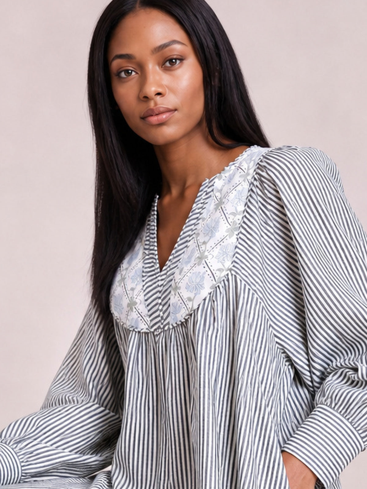 Model wearing a gray-and-white striped floral yoke dress with a V-neckline, gathered waist, and long voluminous sleeves with banded cuffs.