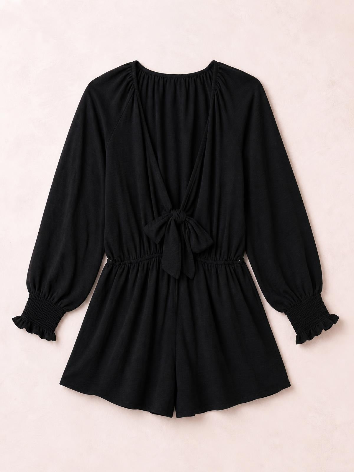 Black tied flounce sleeve plunge romper with long lantern sleeves, gathered ruffled cuffs, an elastic waist, and flowing short legs.