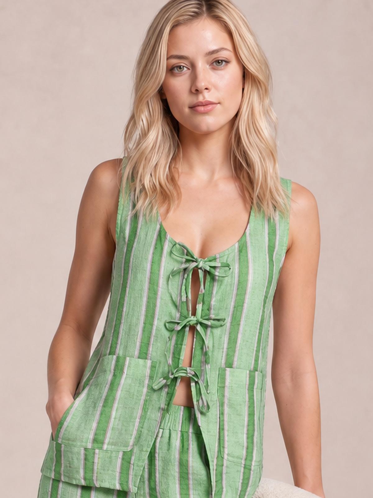 Model wears a green vertically striped top and matching pants set, featuring a sleeveless silhouette, multiple tied-front closures, and visible patch pockets.