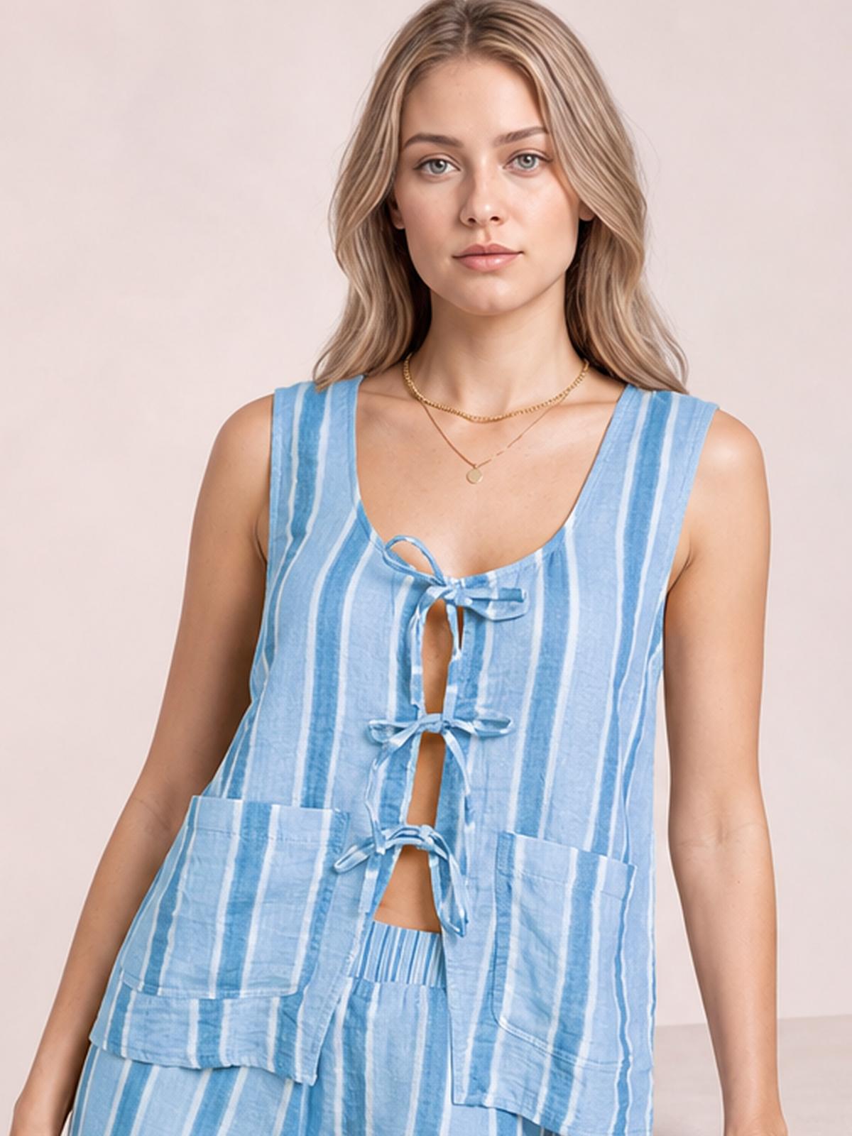 Model standing facing forward in a light blue and white striped top and pants set, featuring a sleeveless tied front, open center, and practical pockets.