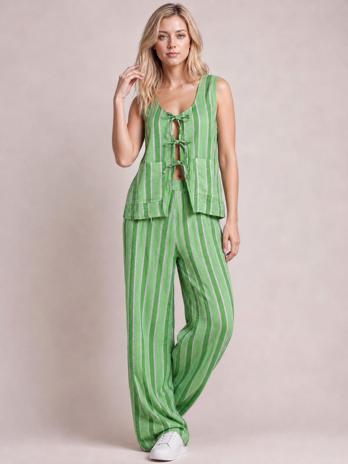 Model poses in a green striped top and pants set with a tied front, sleeveless silhouette, oversized pockets, and relaxed wide-leg trousers.