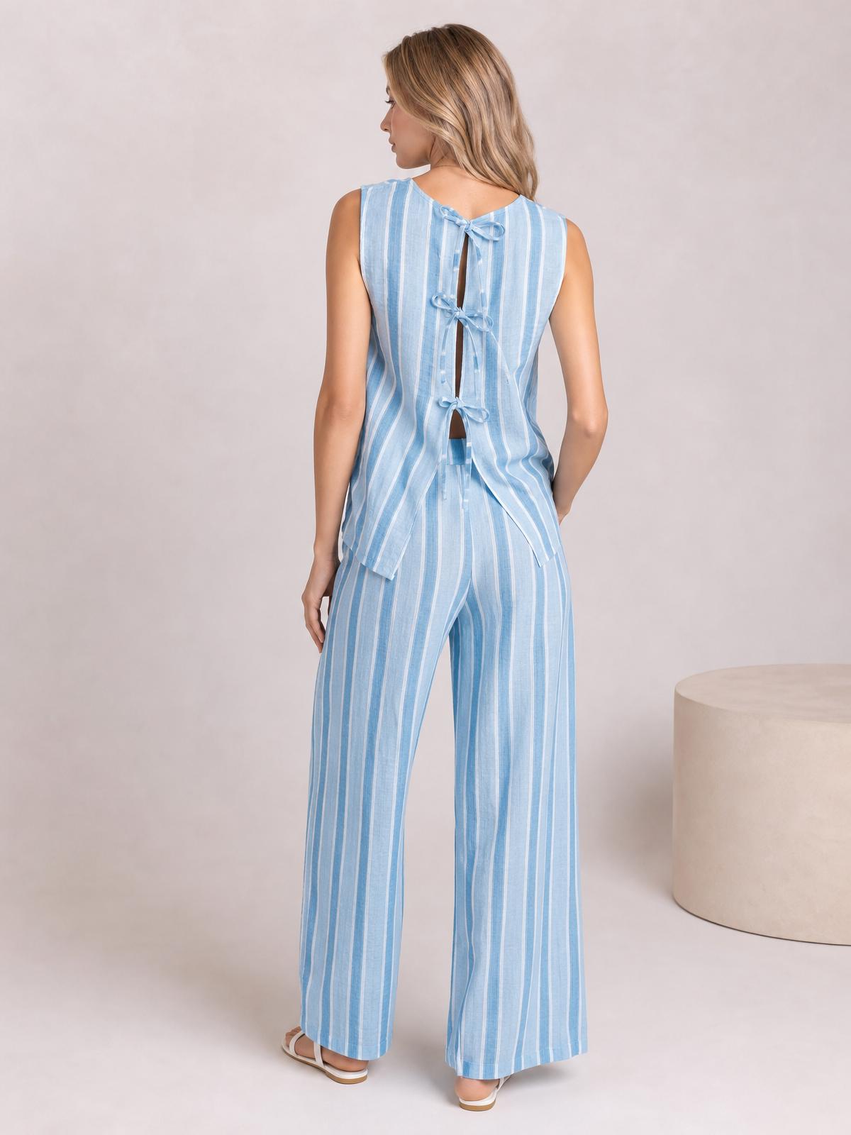 Model stands with her back turned in a light blue striped top and matching wide-leg pants, featuring a tied open back and relaxed silhouette.