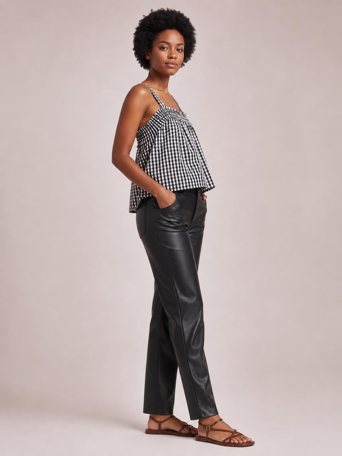 Model wears a black-and-white textured tied-front square-neck cami with thin straps and a loose, flared silhouette, posing with one hand in her pocket.