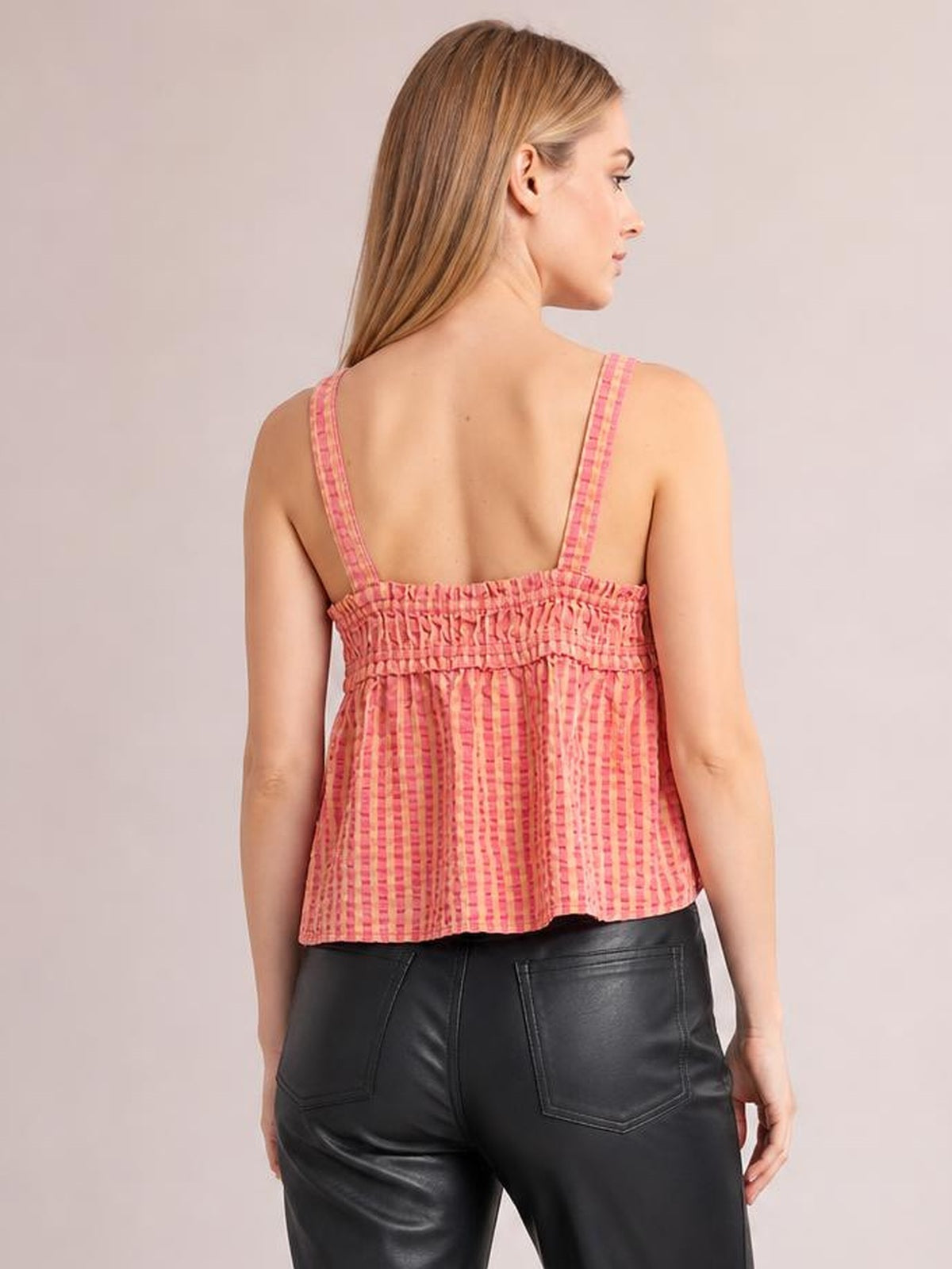 Model shown from behind wearing a pink textured cami with wide straps, a smocked back panel, and a relaxed flared silhouette.
