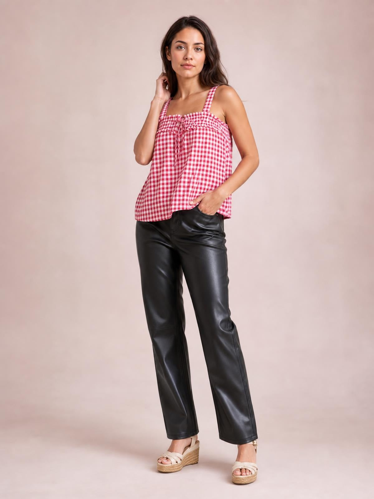 A model poses in a pink-and-white textured gingham cami with a square neckline, slim straps, tied front detail, and relaxed flowy silhouette.