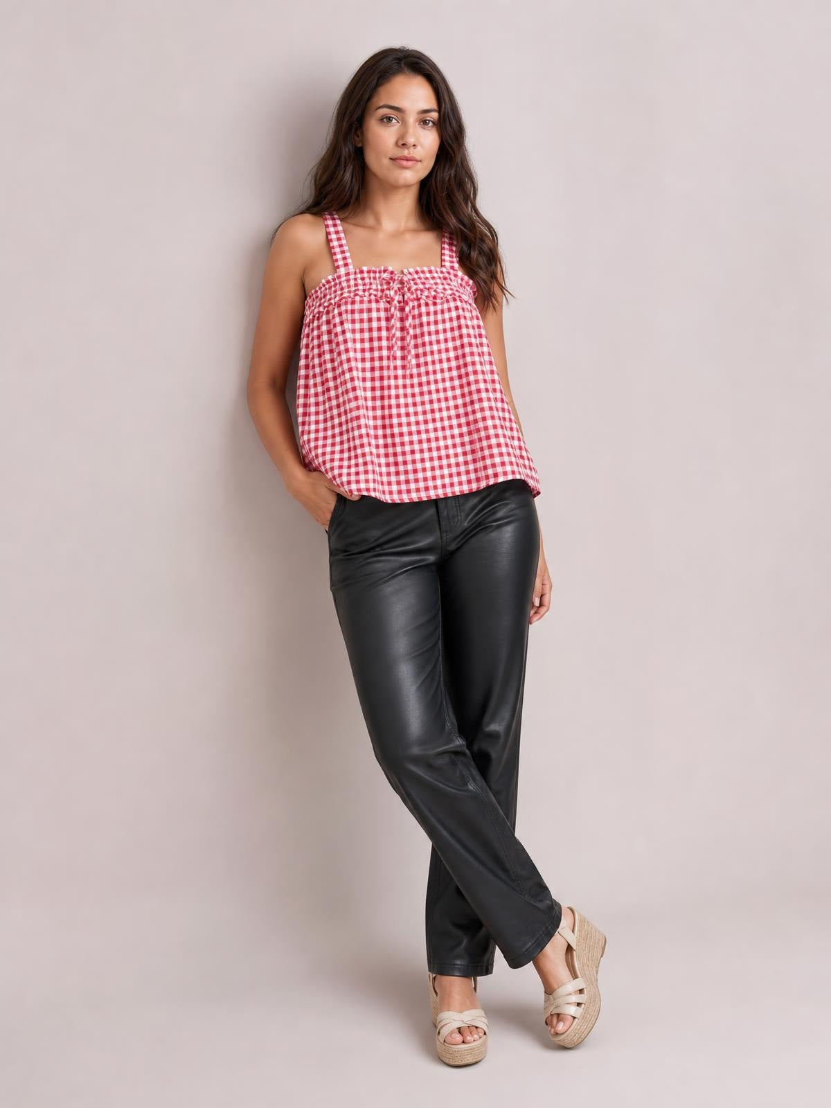 A model poses in a red-and-white textured gingham cami with a square neckline, shoulder straps, tied front, and relaxed silhouette.
