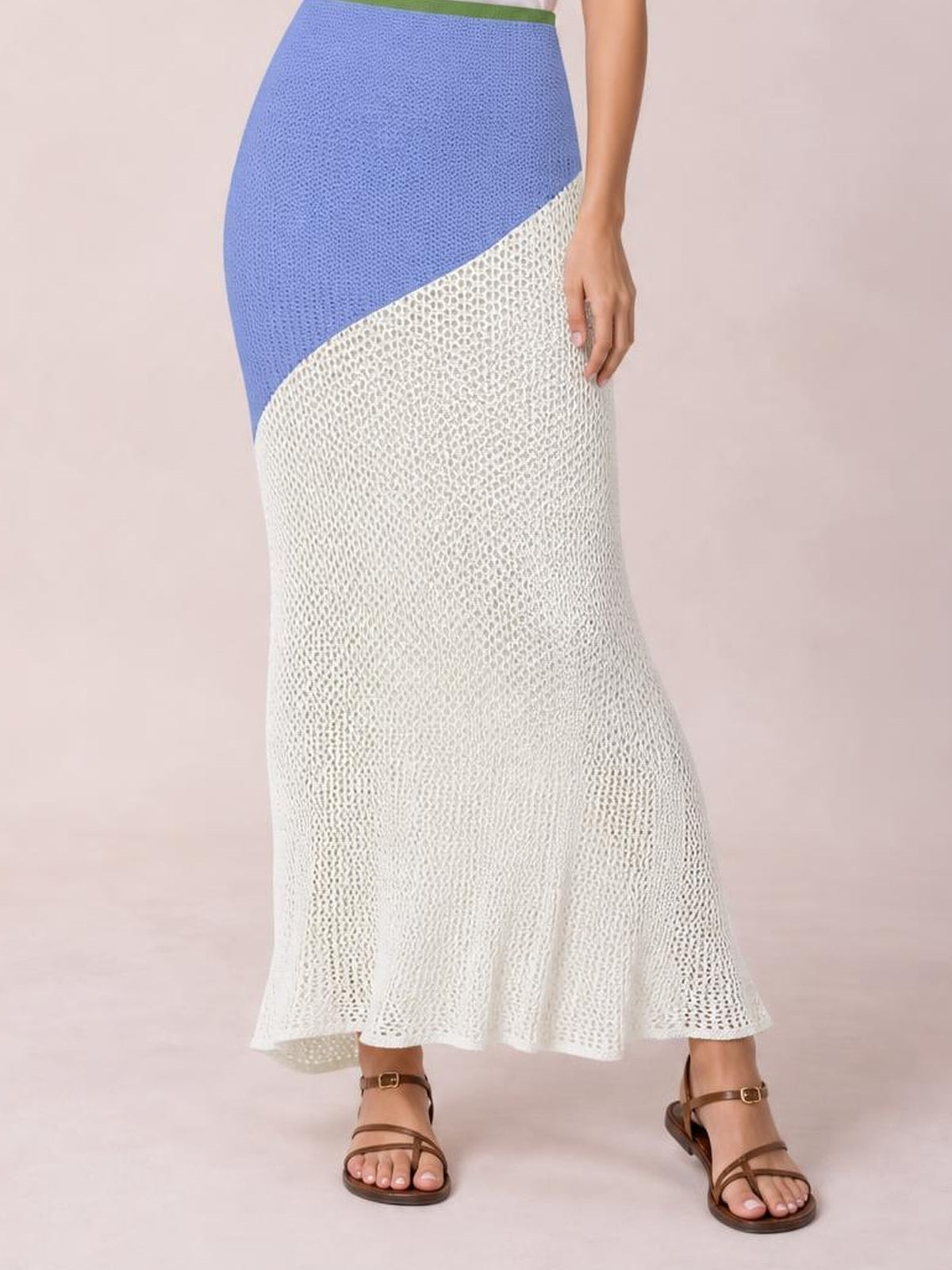 Model stands in a tied cover-up set with a blue high-waisted panel and white openwork maxi skirt, fitted through the hips with a softly flared hem.