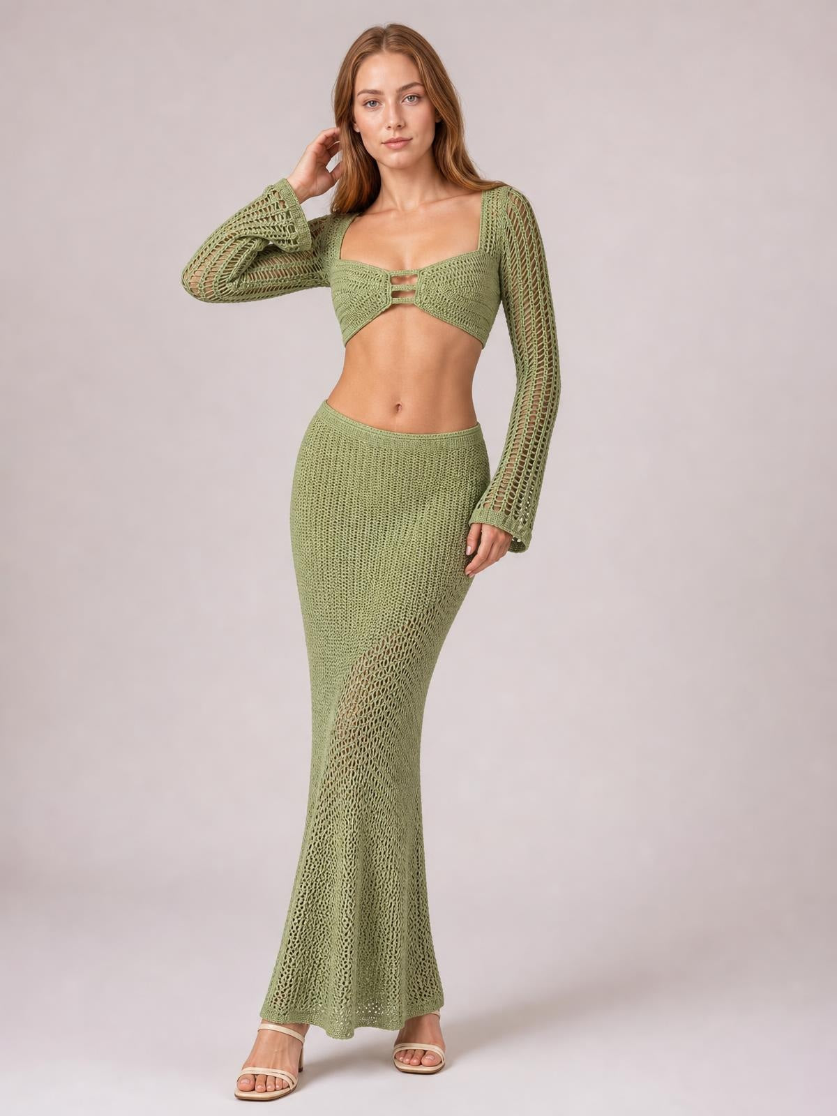 Model poses in a sage green tied long sleeve top and skirt cover up set with openwork sleeves, a cropped cutout bodice, and fitted floor-length silhouette.