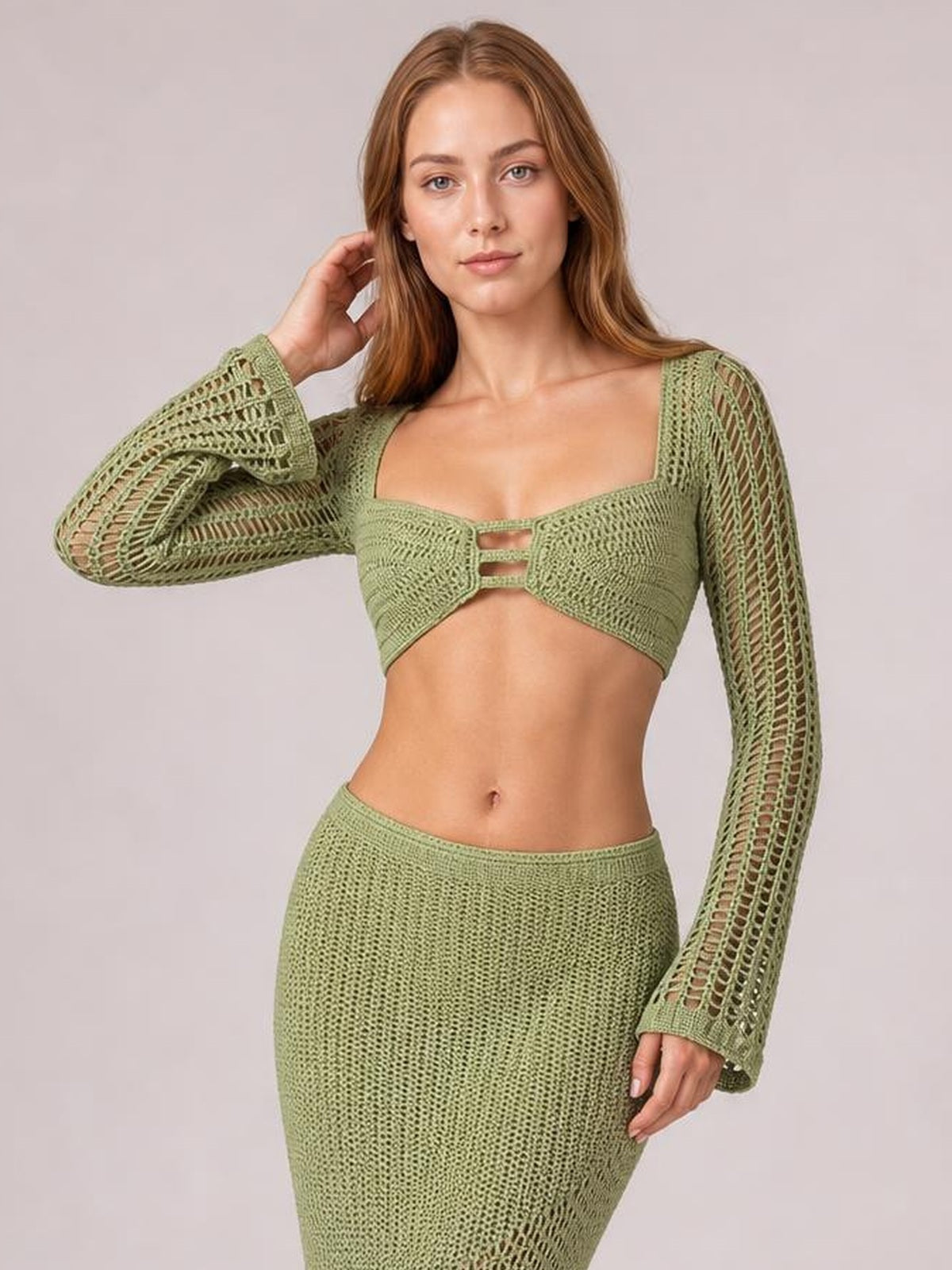 Model poses in a sage green tied long sleeve top and matching high-waisted skirt cover-up set with openwork sleeves and a fitted silhouette.