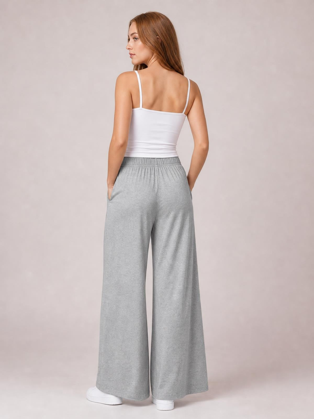 Model shown from the back wearing gray tied pocketed wide-leg pants with an elastic waistband and relaxed, flowing silhouette.