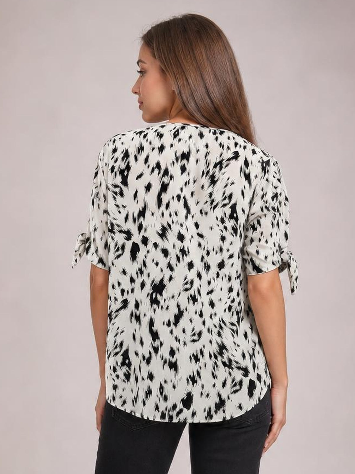 Model shown from behind wearing a white and black printed boat neck blouse with tied three-quarter sleeves and a relaxed, straight silhouette.