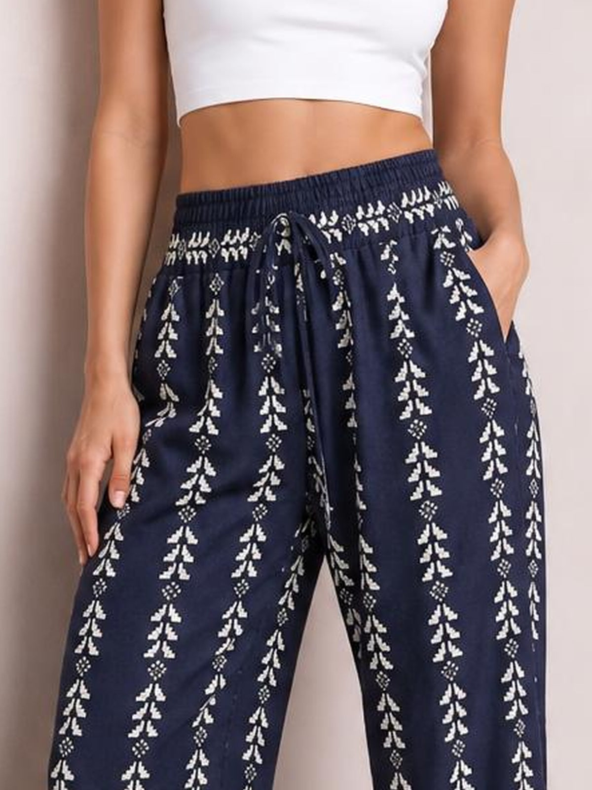 Model shown from the waist down wearing navy printed high-waist pants with a tied drawstring, elastic waistband, side pockets, and a wide-leg silhouette.