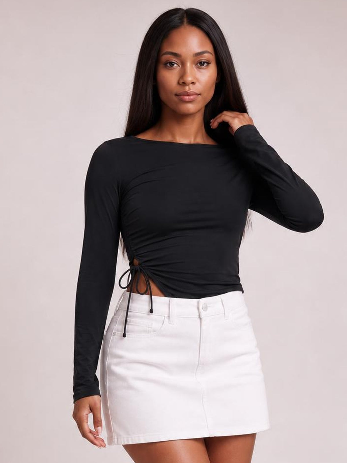 Model wears a black round-neck long-sleeve T-shirt with a fitted silhouette, ruched side slit and tie detail, posing with one hand near her shoulder.
