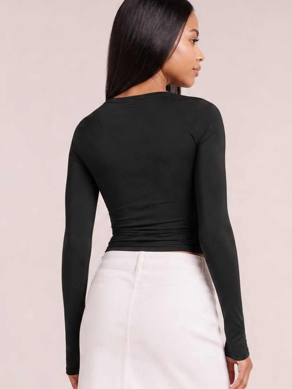 Model shown from the back in a fitted black round-neck long-sleeve T-shirt with a cinched, tied waist and smooth stretch silhouette.