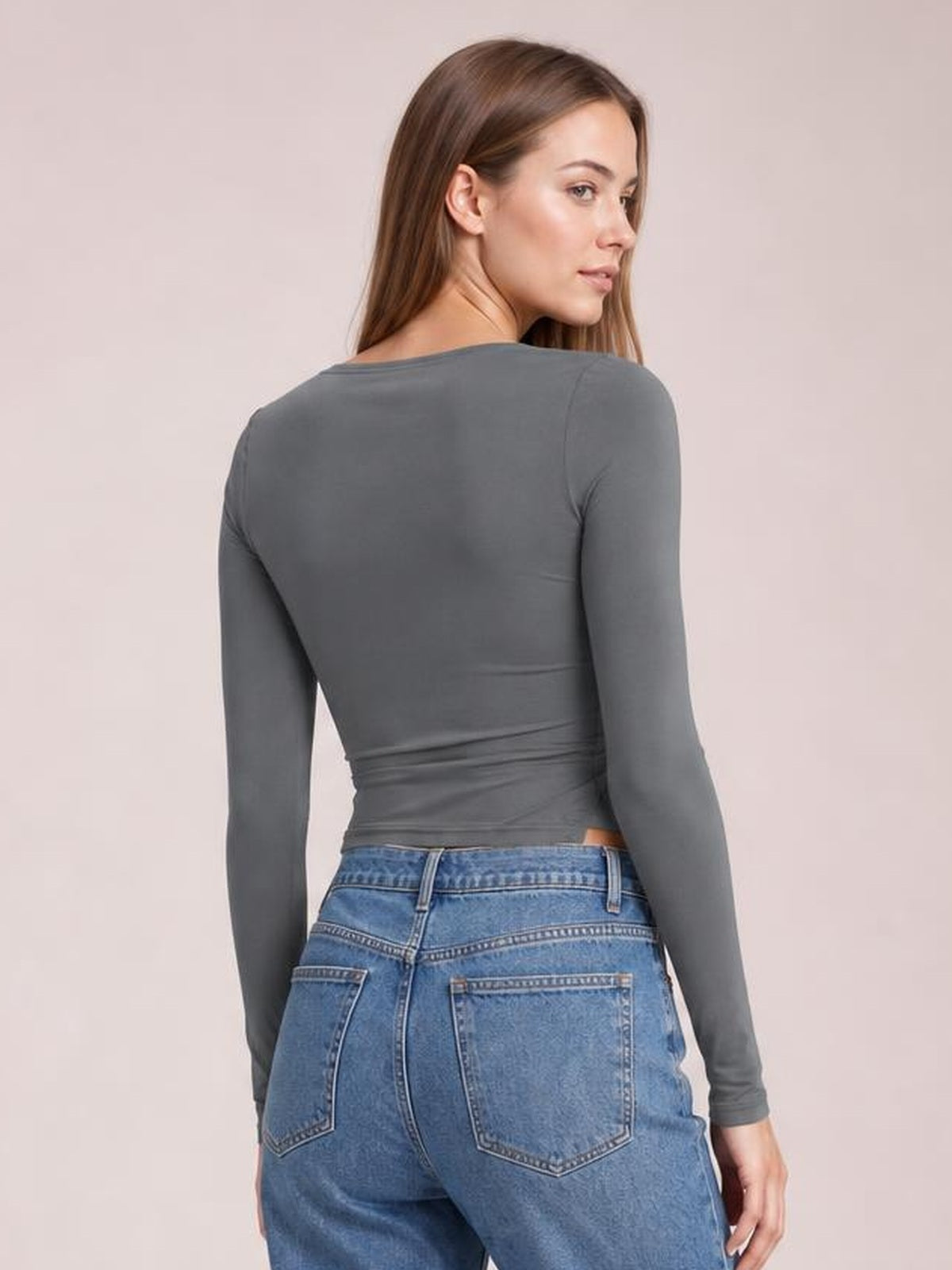 Model looks over her shoulder wearing a charcoal gray tied slit round-neck long-sleeve T-shirt with a fitted silhouette and gathered waist detail.